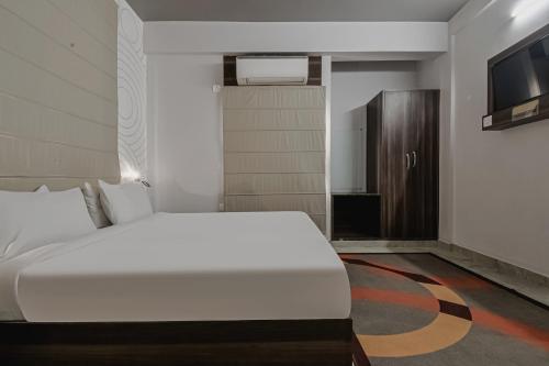 a bedroom with a large white bed and a television at Super Townhouse Vidya Vihar in Patna