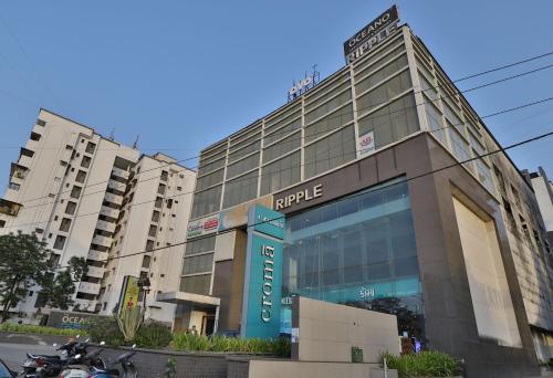 a large building with a sign in front of it at Hotel O Ripple Mall in Surat
