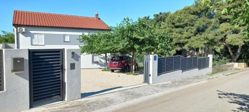 a gate in front of a house with a car in the driveway at lastva 1&2 in Sveti Filip i Jakov