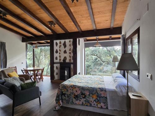 a bedroom with a bed and a living room with a fireplace at Nuevo Ecolodge Cabañeros in Retuerta de Bullaque