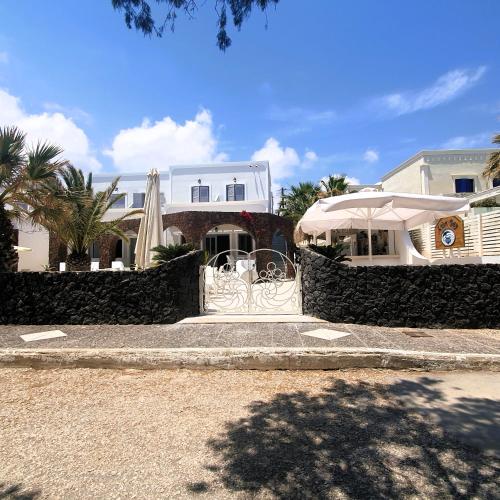 a white house with an umbrella in front of it at Arion Bay Hotel Santorini in Kamari