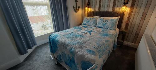 a bedroom with a bed with a blue and white comforter at Trentham House in Paignton