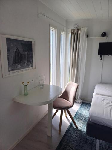 a white room with a table and a chair and a bed at Nybyggd gäststuga in Färjestaden