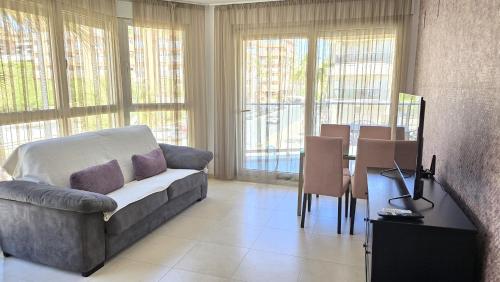 ein Wohnzimmer mit einer Couch und einem Tisch mit Stühlen in der Unterkunft BEACH VALENCIA LUXURY A36-22 Apartment with terrace and sea views in Valencia
