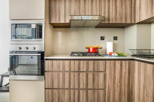 a kitchen with a stove and a microwave at Comfy 1BR w Cinema Room Business Centre Pool Table and Sauna in Dubai