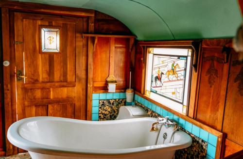 une baignoire dans une salle de bain avec une fenêtre dans l'établissement Magnifique Roulotte Bohème 1930, à Mézos