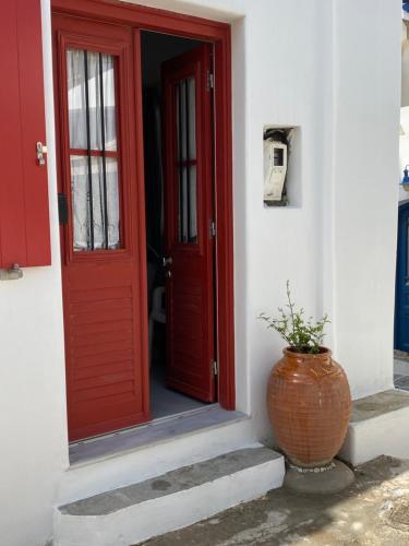 a red door and a vase sitting outside of a building at Agioutanti Spot in Kithnos