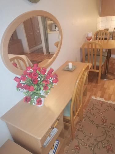 a table with a vase of flowers and a mirror at Yksiö upealla järvinäkymällä Termessä in Ikaalinen
