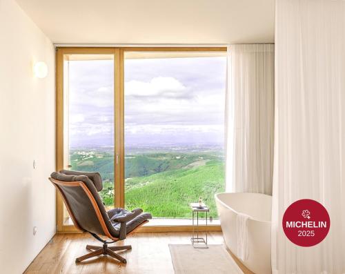 a bathroom with a tub and a chair in front of a window at Casas Da Lapa, Nature & Spa Hotel in Seia