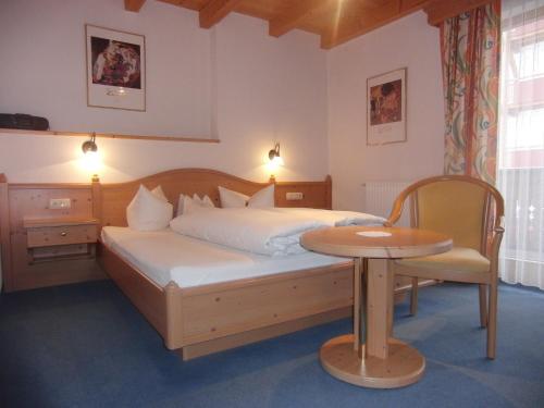 a bedroom with a bed and a table in it at Hotel Garni Elfriede inklusive Super Sommer Card in Serfaus