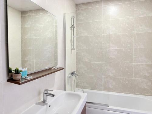 a bathroom with a sink and a tub and a mirror at green diamond 3 bedroom in Tbilisi City