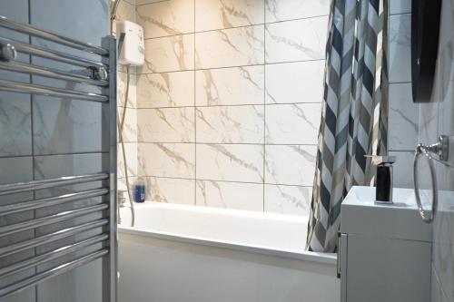 a bathroom with a shower and a tub and a sink at Cosy 3 Bedroom Apartment Near The O2 in London