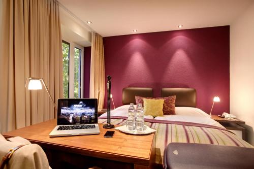 a bedroom with a desk with a laptop on a bed at Strandhotel Alte Donau in Vienna