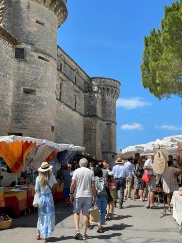 a group of people walking around a market in front of a castle at Maison de village avec vue panoramique proche Gordes in Joucas