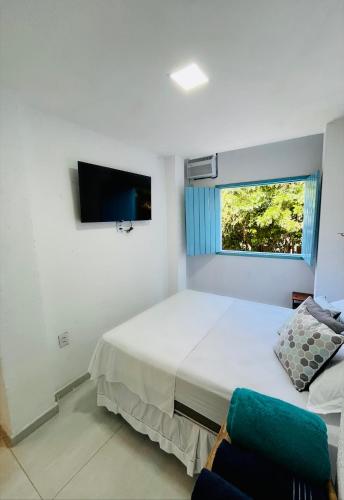 a white bedroom with a bed and a window at CASINHA JASMIM, vila florescer, centro histórico!! in Piranhas