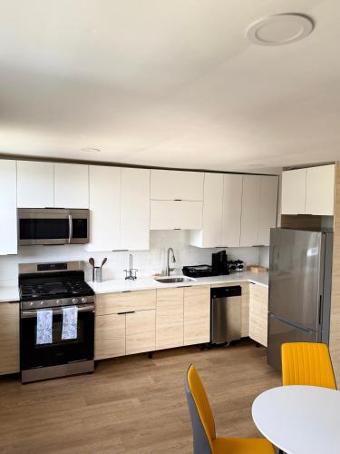 a kitchen with white cabinets and a table with chairs at 15 mins to NYC-Great Apartment Great for Family in West New York