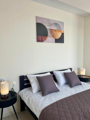 a bedroom with a bed with two tables and a painting at apartments in Ternopil city in Ternopilʼ