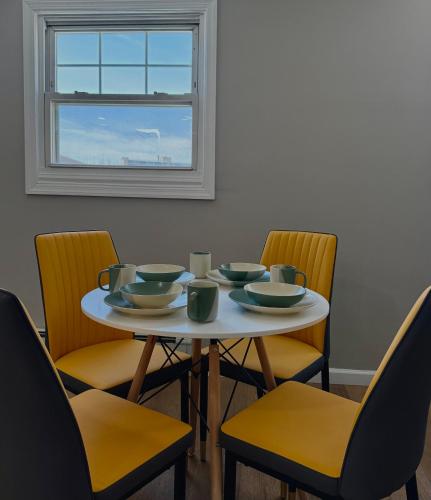 a table with bowls and chairs and a window at 15 mins to NYC-Great Apartment Great for Family in West New York