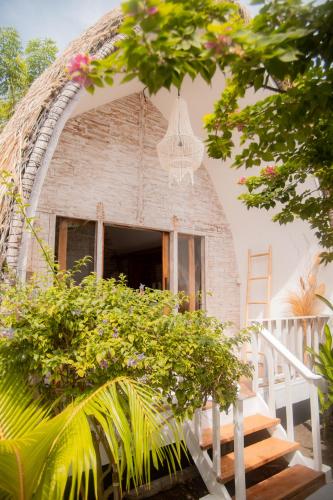 a building with a thatch roof with a staircase and a window at Les Vagues - Hotel Villa & Beach Club - Gili Air in Gili Air