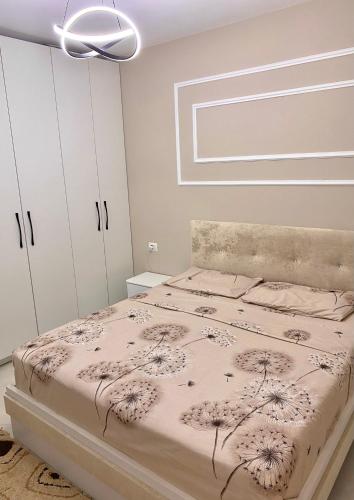 a bedroom with a bed with a flower pattern on it at Saranda Apartment in Polisi i Vogël