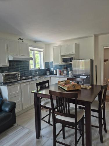 a kitchen with a wooden table and chairs and a kitchen with white cabinets at Séjour Flèche du fjord vue Saguenay Mont Valin in Saint-Fulgence