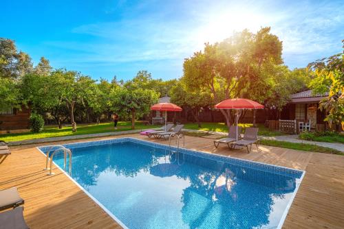 a swimming pool with two umbrellas and a house at Mandarin Bungalow in Alanya