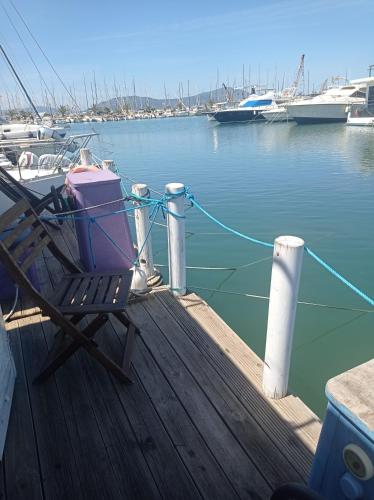 a chair on a dock with boats in the water at Houseboat BluSeaDream Alghero in Alghero