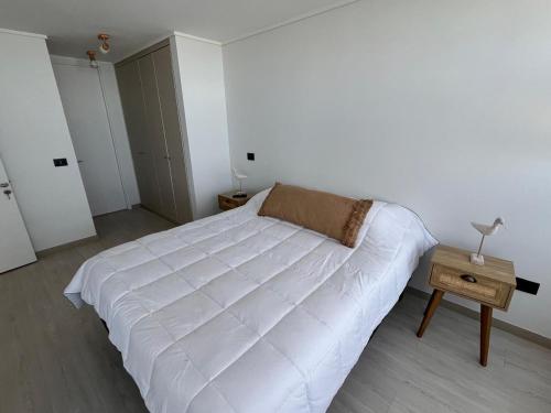 a white bed in a white room with a table at Exclusivo Laguna del Mar in La Serena