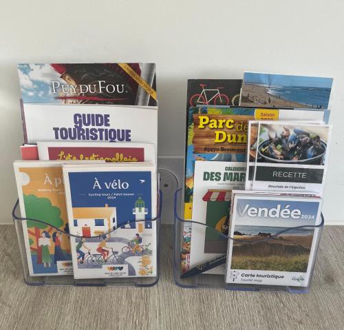 a pile of books sitting on top of a table at Sables des Dunes, jolie maison neuve tout confort, vacances famille ou entre amis, 500 m plage in Brétignolles-sur-Mer