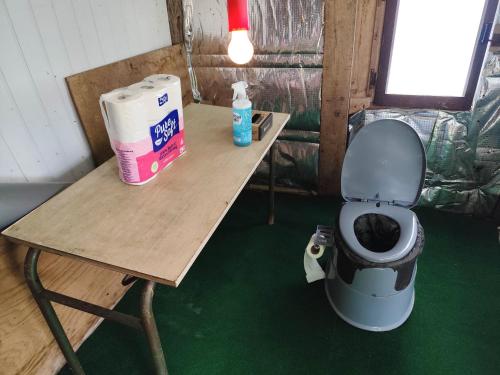 des toilettes posées sur une table à côté d'une table avec une boîte dans l'établissement Emplacement au bord d'un petit étang, à Chaudenay