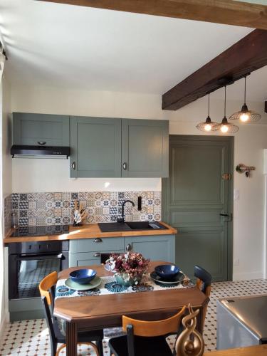 une cuisine avec des placards verts et une table en bois dans l'établissement Le Cocon Charentais, à Saint-Même-les-Carrières