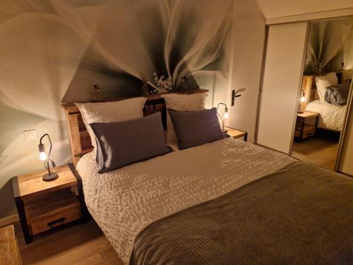 een slaapkamer met een bed met 2 lampen en een spiegel bij Gîte du Bois l'Abbé in Saint-Martin-Boulogne