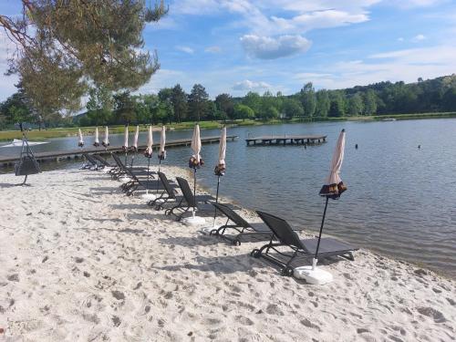a row of chairs with umbrellas on a beach at SeeRuhe - Mobilheim Grosssteinbach in Grosssteinbach
