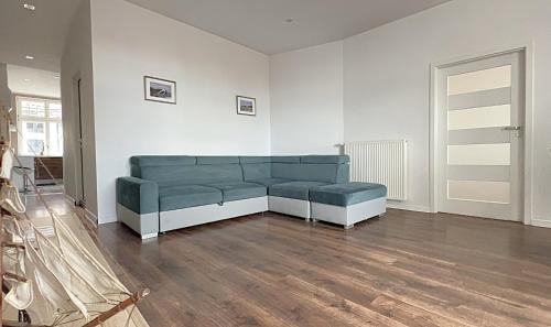a blue couch sitting in a white room at Long Island in Grudziądz