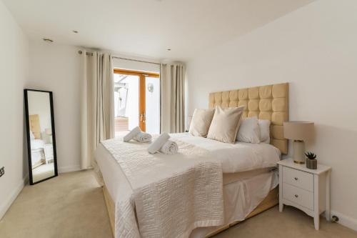 a white bedroom with a large bed and a mirror at In the middle of Cardiff City centre in Cardiff
