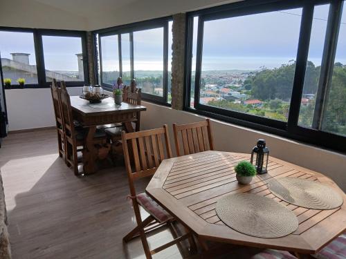 a dining room with a table and chairs and windows at Casa Colmeia in Esposende