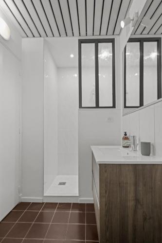 La salle de bains blanche est pourvue d'un lavabo et de fenêtres. dans l'établissement Magnifique appartement - 15 minutes a pieds PALAIS, à Cannes