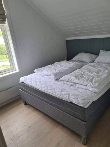an unmade bed in a room with a window at Solheimhuset - feriehus nær Tjøme og VerdensEnde in Tokenes