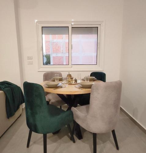 a dining room table with green chairs and a window at Arabic Apartment in Safaga