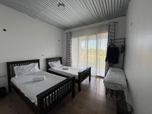 a room with two beds and a table and a window at Twenty ritz in Migori