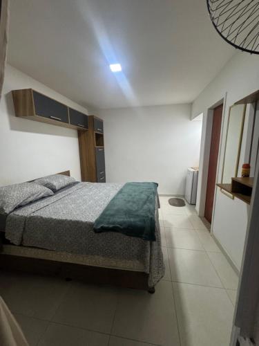 a bedroom with a bed with a green blanket at Suite Dunas do Peró in Cabo Frio