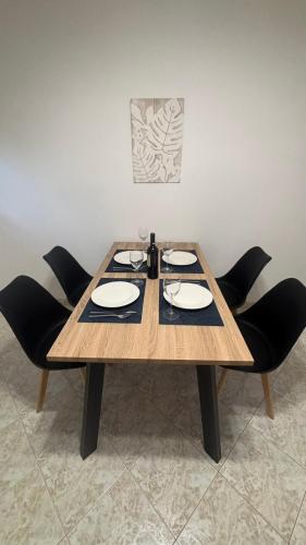 a wooden table with black chairs and plates on it at Lemon Suites 2 in Mytilini
