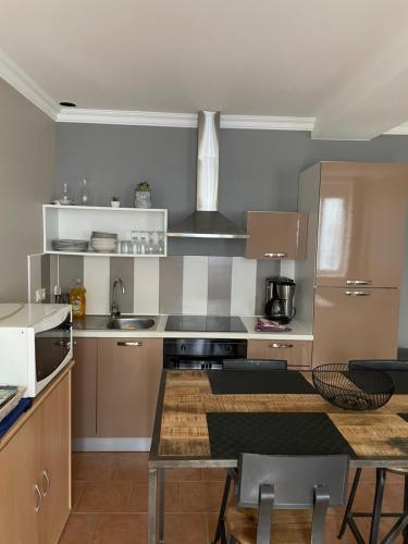 eine Küche mit Geräten aus Edelstahl und einem Tisch in der Unterkunft Maison de plain-pied avec un grand jardin in Malicorne-sur-Sarthe