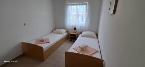 two beds in a small room with a window at Apartmani BRNADA in Trogir