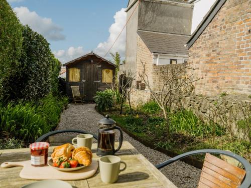 a table with a plate of bread and coffee cups at Enchanted Rose Garden House in Falmouth
