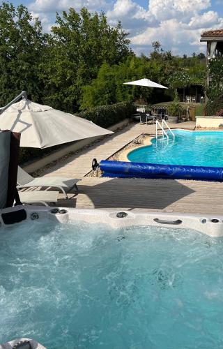 une grande piscine d'eau bleue avec un parasol dans l'établissement Lake Noble, à Saint-Germain-lʼAiguiller