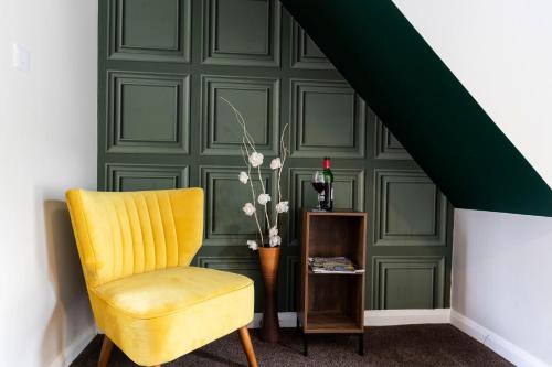 a yellow chair in a room with a green wall at The Storybook Stay in Guisborough