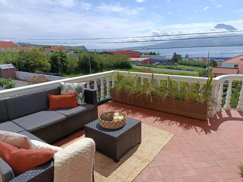 a patio with a couch and tables on a balcony at Dutra's House in Horta