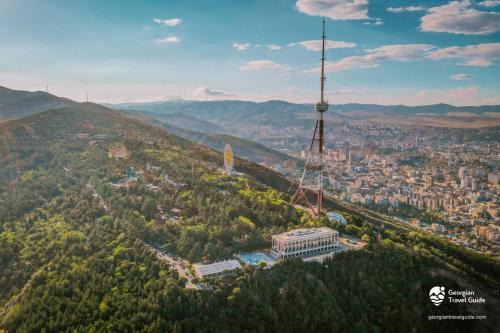 a view of a city with a tv tower on a hill at Solo Apartment in Tbilisi City