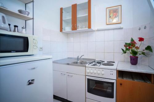 a white kitchen with a sink and a microwave at Villa MAR in Orebić